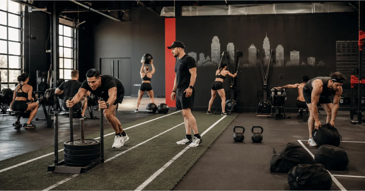 Where to Train for HYROX in Dallas: How to Choose a HYROX Training Gym Athletes complete sled pushes, rowing, wall balls, and functional fitness exercises during a structured HYROX training session under coach supervision.