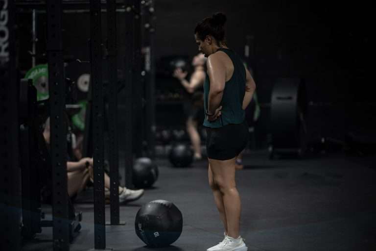 HYROX Weights by Division: Every Station, Every Category (KG & LBS) Athlete resting over the medicine ball between wall ball sets at Hunger in the Wild