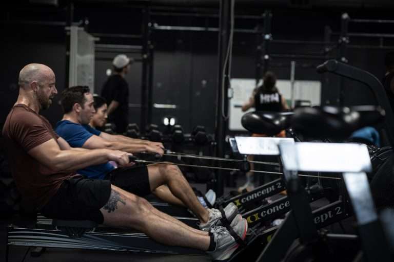 Hunger In The Wild vs. Big-Box Gyms in Dallas: An Honest Comparison Three athletes at the catch on Concept2 rowers during a HYROX rowing interval at our Dallas gym