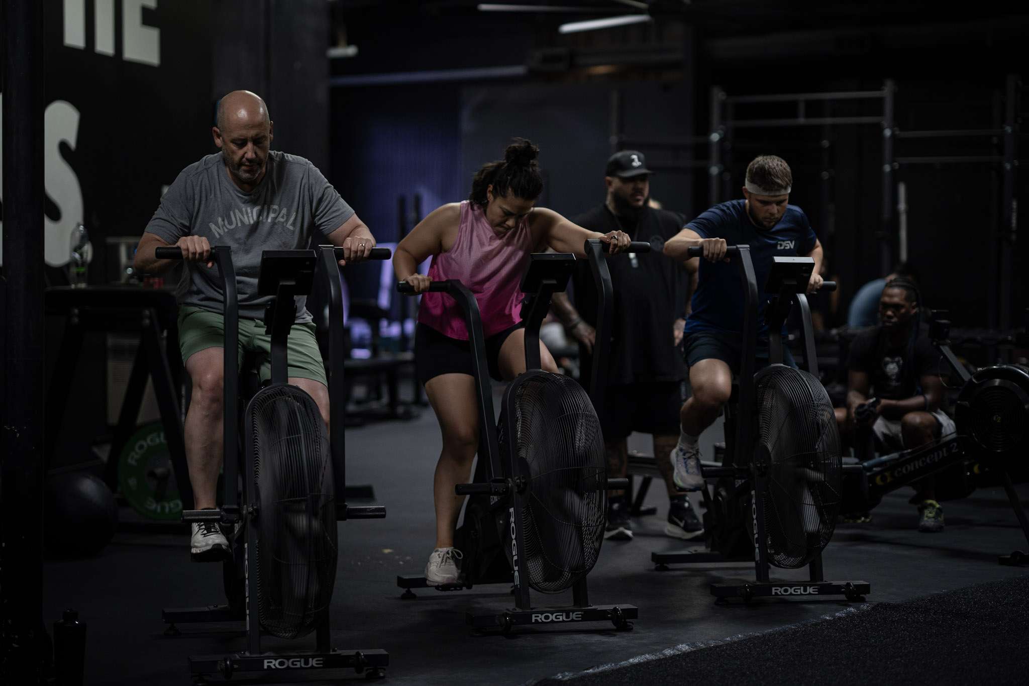 HYROX Pacing Strategy: Race Your First (or Fastest) Race HYROX class members grinding through an interval on Rogue Echo Bikes