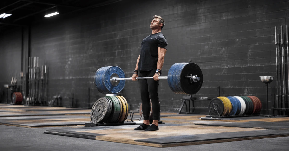 Strength Training for HYROX: Why Getting Stronger Makes You Faster on Race Day Athlete performs a heavy deadlift on a lifting platform, demonstrating maximal strength development for HYROX performance and race preparation.