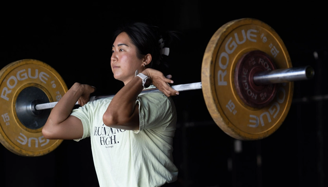 Best Weight Training Gym in Dallas for Serious Athletes Coach watching a woman squat with a medicine ball at Hunger in the Wild Gym.