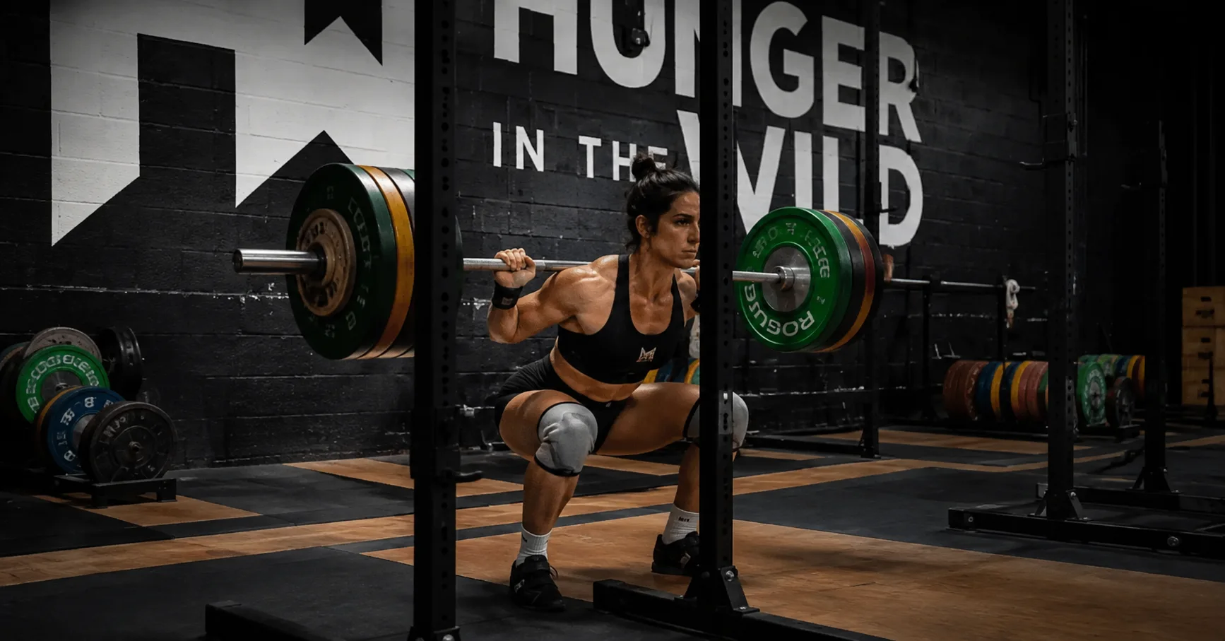 Best Weight Training Gym in Dallas for Serious Athletes Woman performing a heavy barbell back squat at Hunger in the Wild Gym in Dallas.