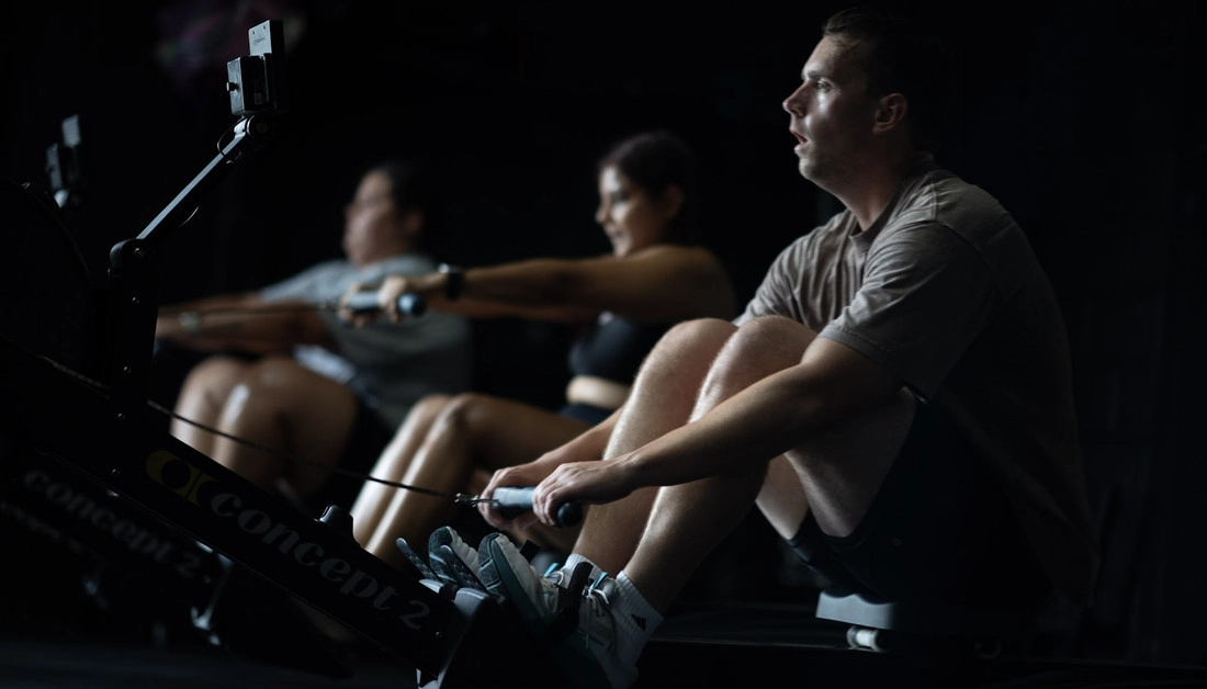 The Best Personal Training Gym in Dallas for Strength and Athletic Performance Man rowing alongside other athletes at Hunger in the Wild Gym.