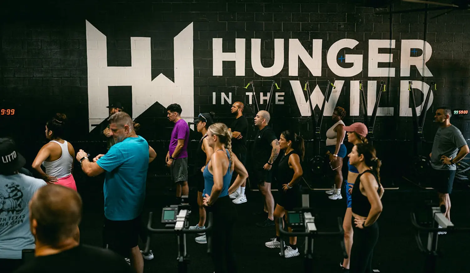 A coached class under the Hunger in the Wild logo wall in the Dallas Design District