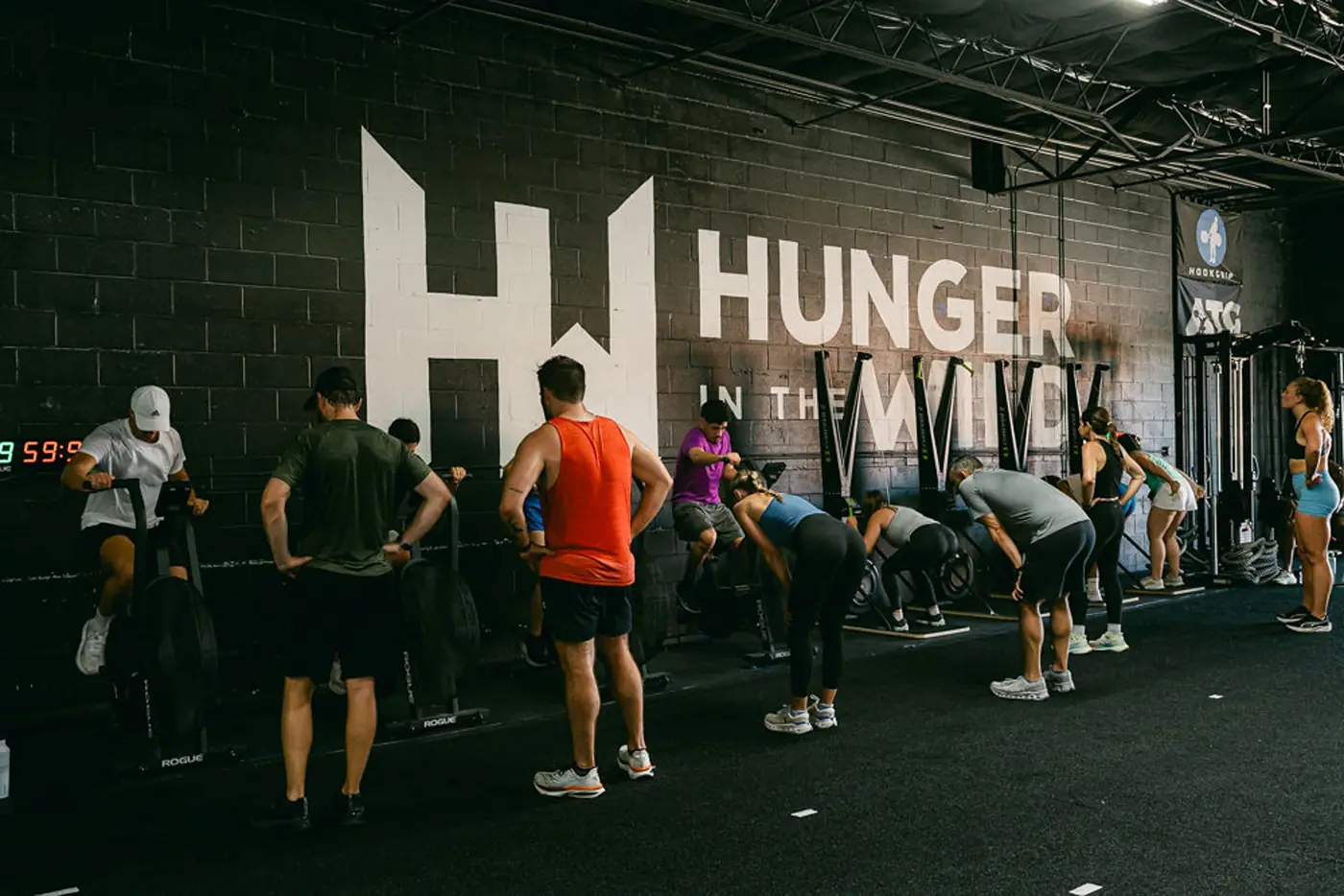 A coached class lined up under the Hunger in the Wild logo wall in the Dallas Design District